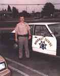 CHP Officer Phil Konstantin with 
a CHP patrol car, 1990.